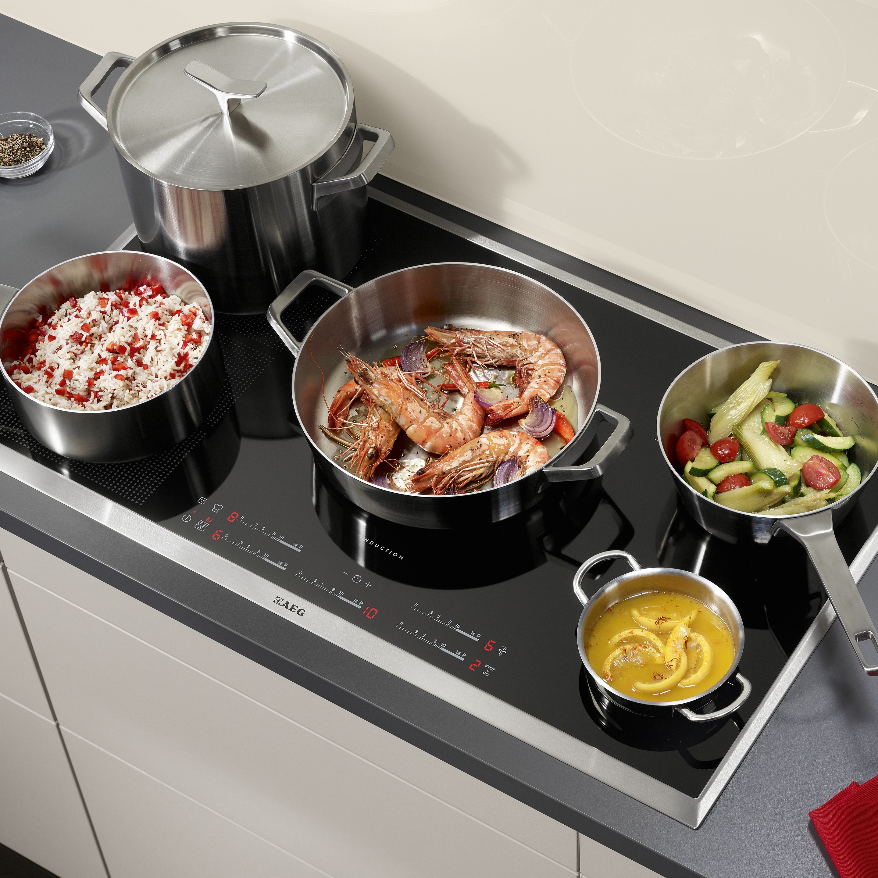 Płyta indukcyjna Electrolux z gotującymi się w naczyniach różnymi potrawami