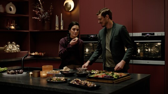 Man and woman preparing food in ktichen.